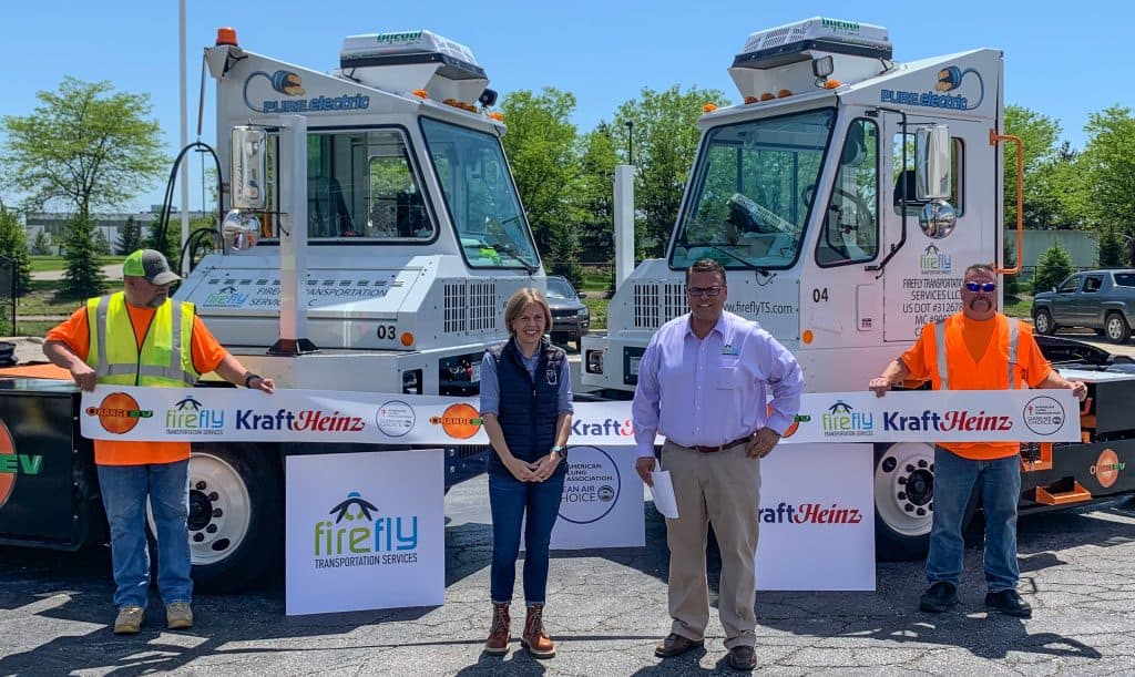 Ribbon-cutting ceremony for Kraft Heinz deployment of Orange EV pure electric terminal trucks via Firefly Transportation Services. Pictured at center: Erin Mitchell, Head of Warehousing for The Kraft Heinz Company, and Mike Bohnstengel, Principal Partner at Firefly Transportation Services.