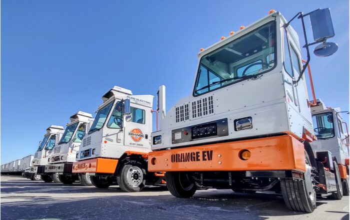 Four white and orange electric yard trucks