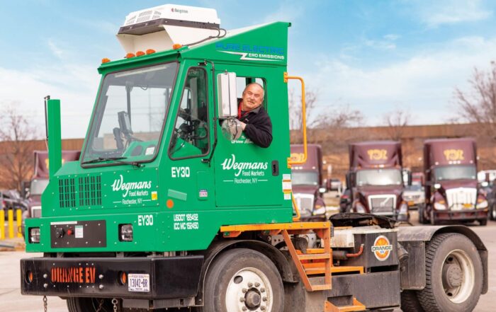A man is driving a green electric yard truck