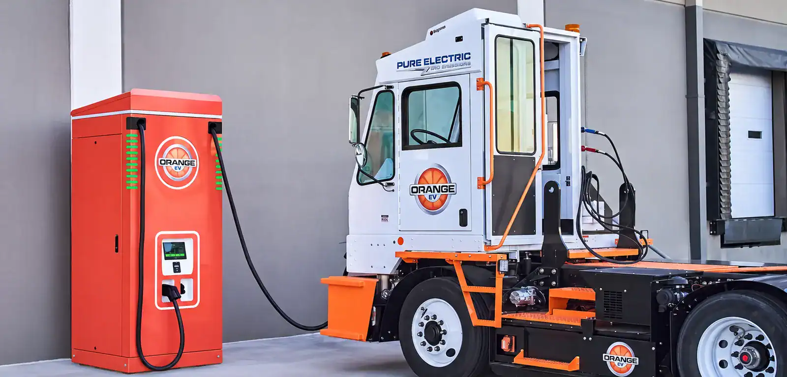 Orange EV electric yard truck plugged into an Orange EV DC fast charger at a distribution center